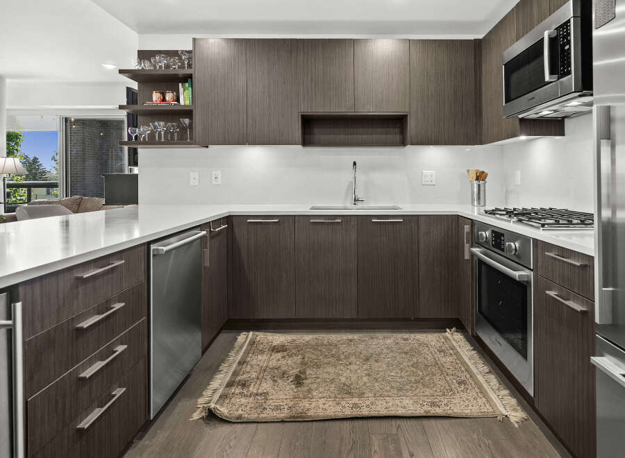 Experience modern luxury in this stunning kitchen, featuring sleek dark wood cabinetry and a pristine white quartz countertop.