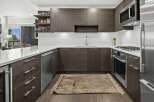 Experience modern luxury in this stunning kitchen, featuring sleek dark wood cabinetry and a pristine white quartz countertop.