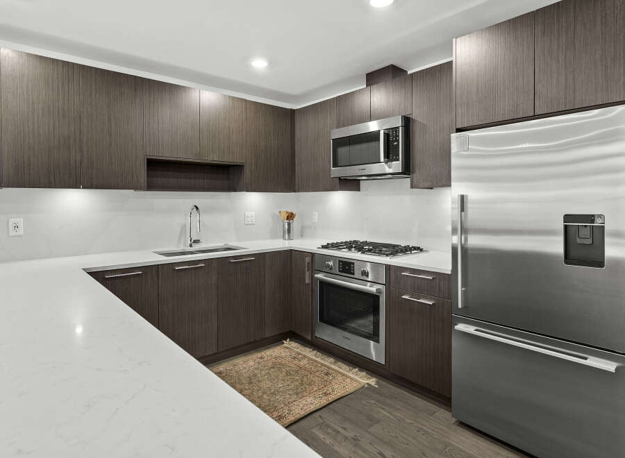 Experience modern living in this sleek kitchen, featuring dark wood cabinetry and pristine white quartz countertops.