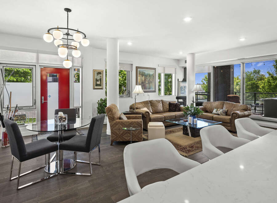 Experience modern living in this spacious open-concept condo, featuring a sleek dining area with a glass-top table and contemporary chairs.