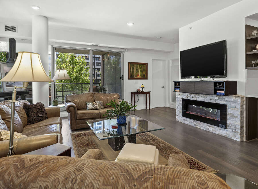 Experience modern living in this stunning condo featuring a spacious living area with a sleek fireplace and a large flat-screen TV.