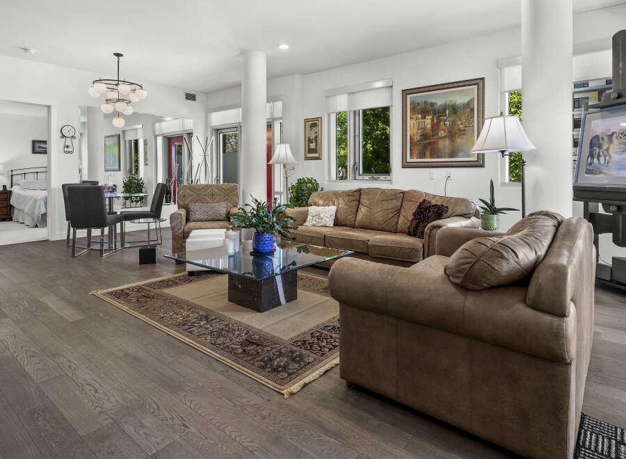 Experience luxurious living in this spacious open-concept home, featuring a beautifully appointed living area with plush leather seating and a striking glass coffee table.