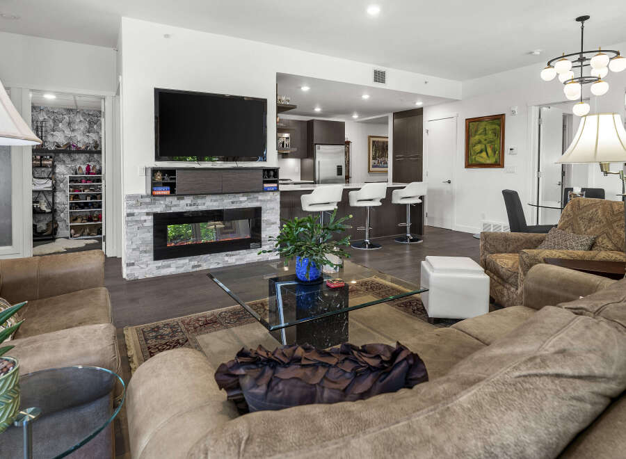 Experience modern living in this stylish condo featuring an open-concept living area with a sleek fireplace and a gourmet kitchen with bar seating.