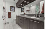 This luxurious bathroom features a sleek double vanity with modern cabinetry and a quartz countertop, complemented by elegant marble tilework.