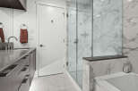 Experience modern luxury in this stunning bathroom, featuring a sleek vanity with ample storage and a sophisticated marble-tiled shower.