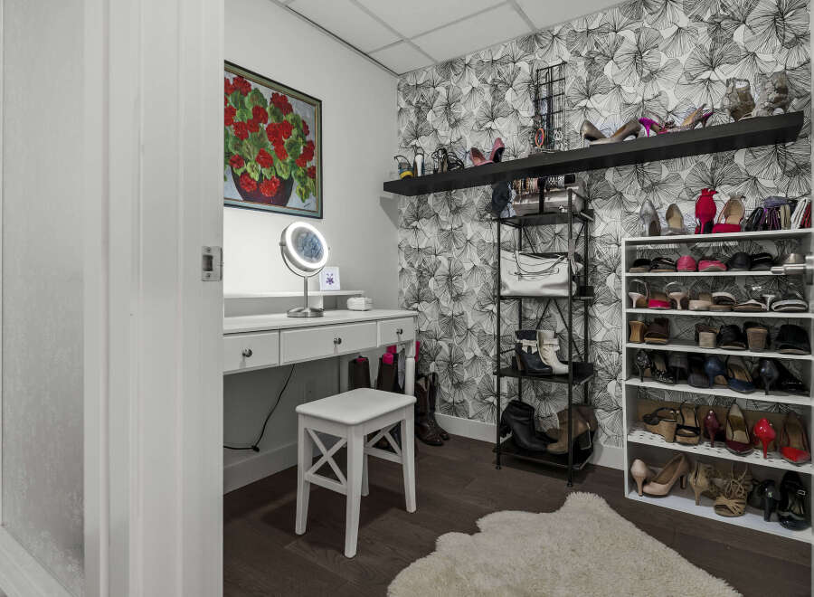 Discover your dream closet with this beautifully organized dressing area, featuring a chic vanity with a lighted mirror and ample storage for all your accessories.