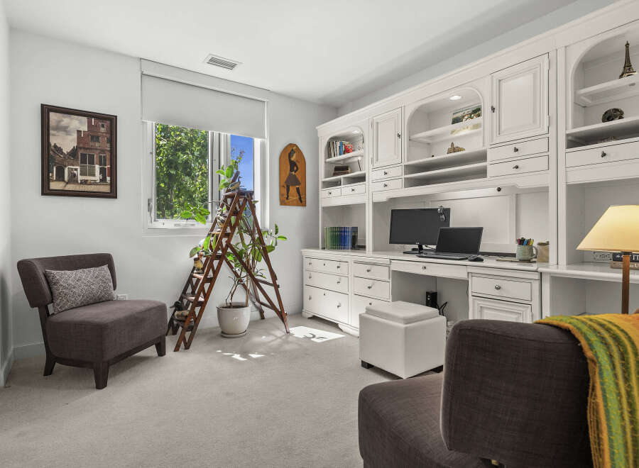 This home office features a built-in white desk with ample storage, including drawers and shelving, perfect for organizing your work essentials.