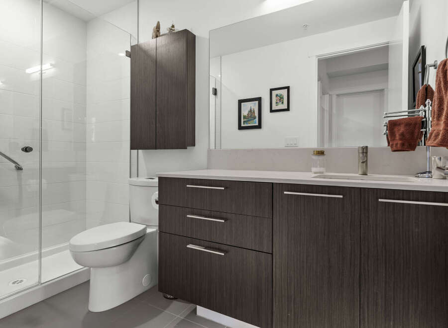 Experience modern luxury in this stunning bathroom featuring a sleek glass-enclosed shower with white subway tiles and a convenient grab bar.
