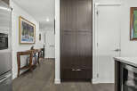 This modern hallway features a sleek, dark wood pantry with brushed nickel hardware, offering ample storage.
