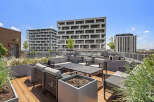 Experience modern urban living with this stunning rooftop patio, featuring comfortable seating and sleek planters.