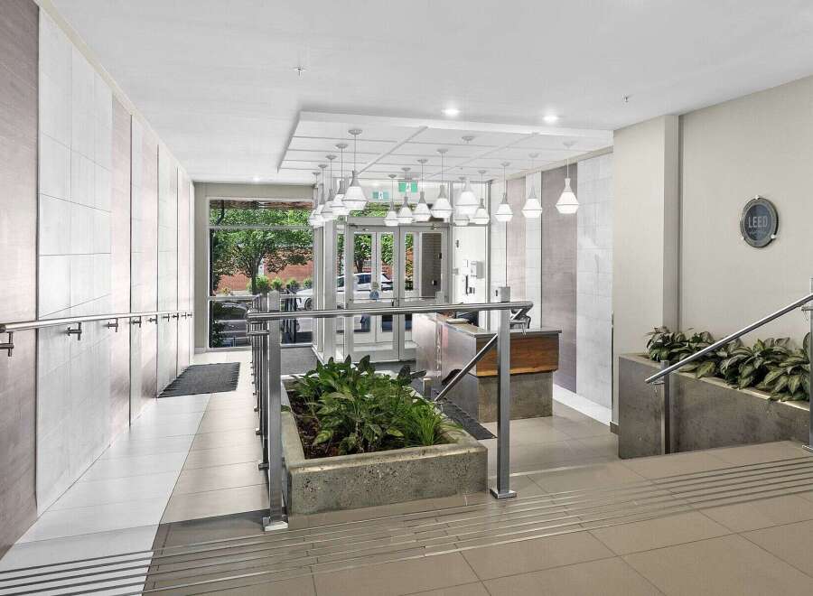 Step into a modern and welcoming lobby featuring a sleek reception desk and elegant pendant lighting.