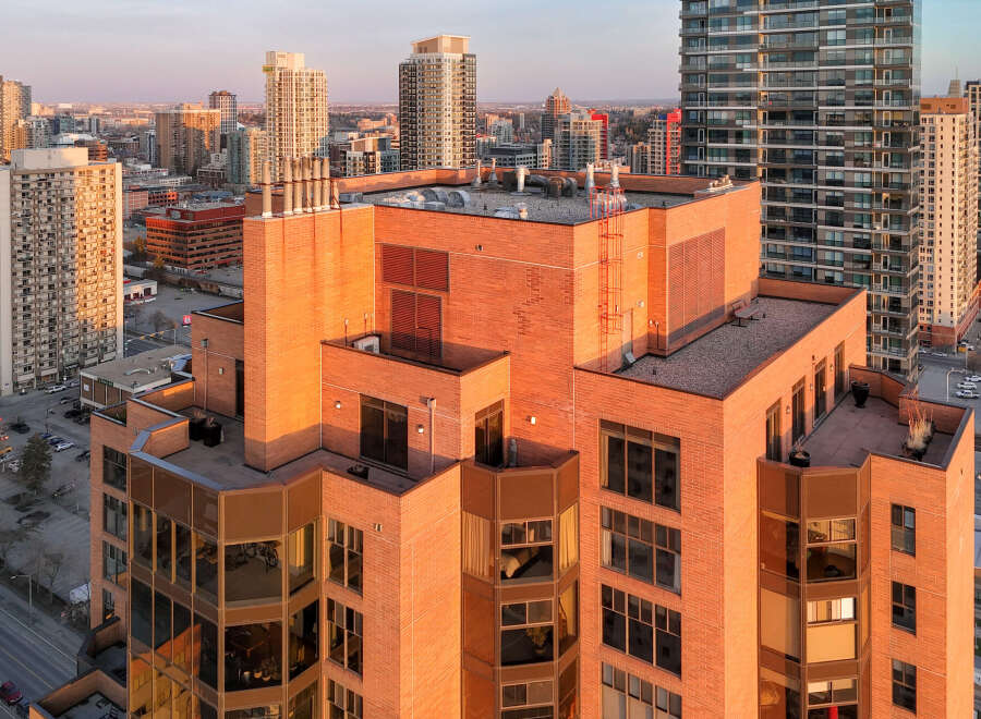 Experience luxury urban living in this stunning high-rise apartment building, bathed in the warm glow of sunset.