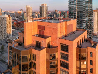Experience luxury urban living in this stunning high-rise apartment building, bathed in the warm glow of sunset.