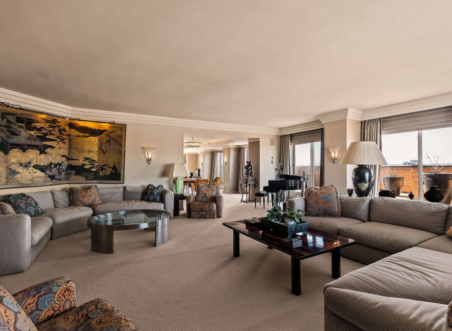 Experience luxurious living in this expansive living room, featuring a grand sectional sofa adorned with decorative pillows and a striking oriental screen.