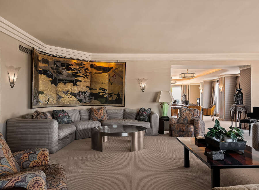 Step into this luxurious living room, featuring a grand sectional sofa adorned with decorative pillows and a striking gold-leaf screen art piece.