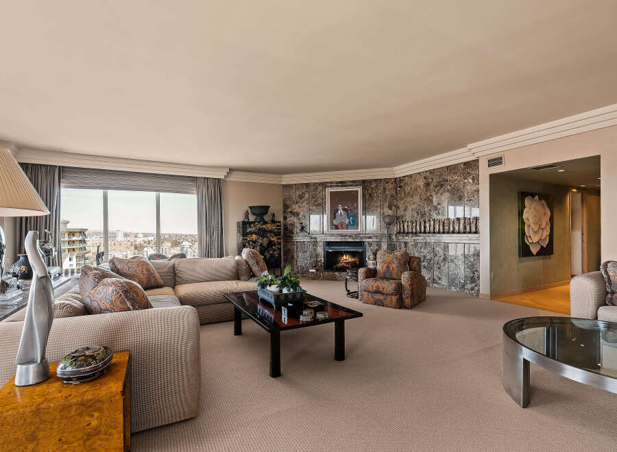 Experience luxury living in this spacious living room, featuring a grand marble fireplace and a comfortable sectional sofa perfect for gatherings.