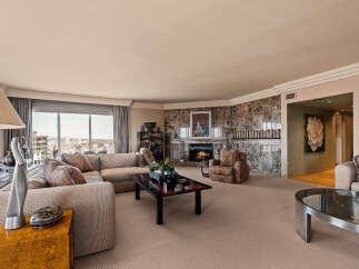 Experience luxury living in this spacious living room, featuring a grand marble fireplace and a comfortable sectional sofa perfect for gatherings.