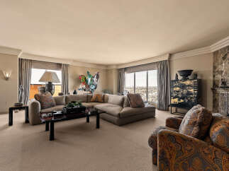 Experience luxurious living in this spacious living room, featuring a large sectional sofa and a plush armchair perfect for relaxation.