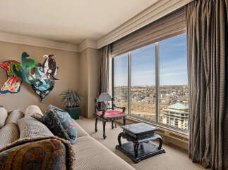 Experience breathtaking panoramic city views from this stunning living room, featuring a large picture window that floods the space with natural light.