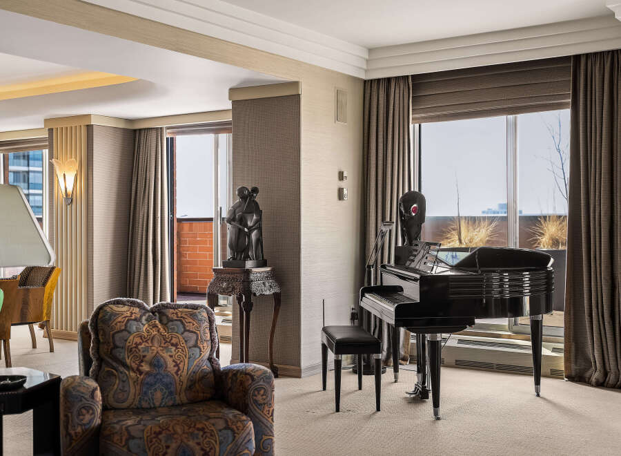 Experience luxury living in this elegant room featuring a grand piano and a comfortable armchair.