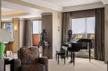Experience luxury living in this elegant room featuring a grand piano and a comfortable armchair.