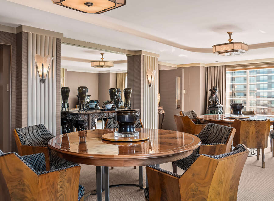 Experience opulent dining in this Art Deco-inspired space, featuring a stunning circular wood dining table surrounded by elegantly upholstered chairs.