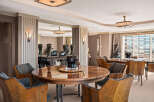 Experience opulent dining in this Art Deco-inspired space, featuring a stunning circular wood dining table surrounded by elegantly upholstered chairs.