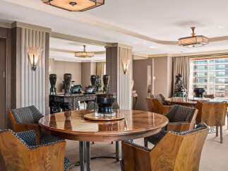Experience opulent dining in this Art Deco-inspired space, featuring a stunning circular wood dining table surrounded by elegantly upholstered chairs.