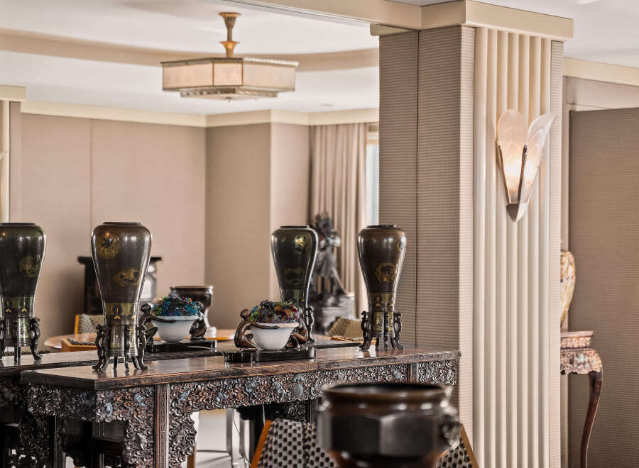 Experience refined living in this elegant space, featuring a stunning console table adorned with antique vases and intricate carvings.