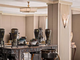 Experience refined living in this elegant space, featuring a stunning console table adorned with antique vases and intricate carvings.