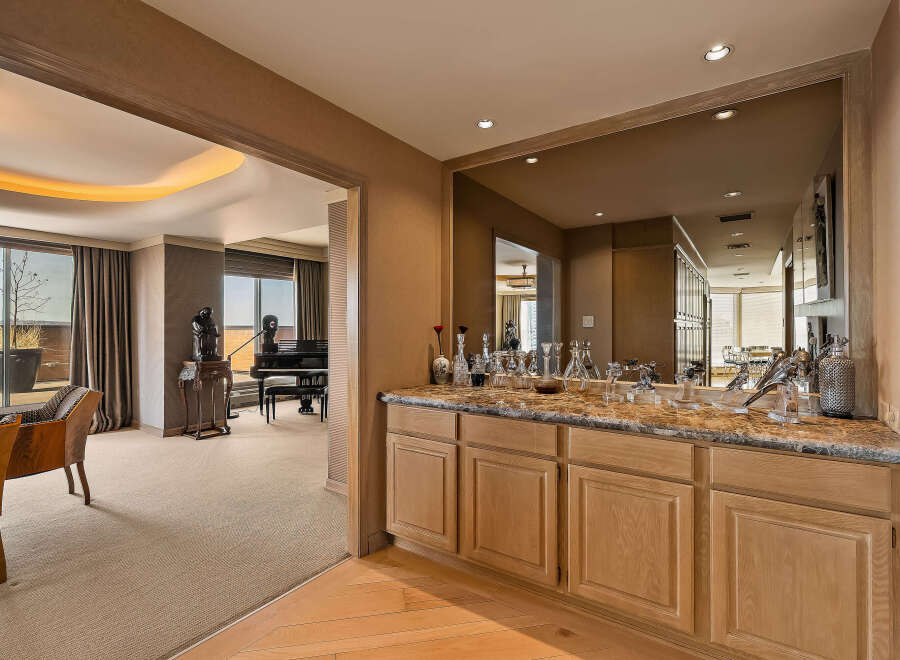 Experience luxury living with this stunning property featuring a sophisticated bar area with a marble countertop and ample cabinetry, perfect for entertaining.