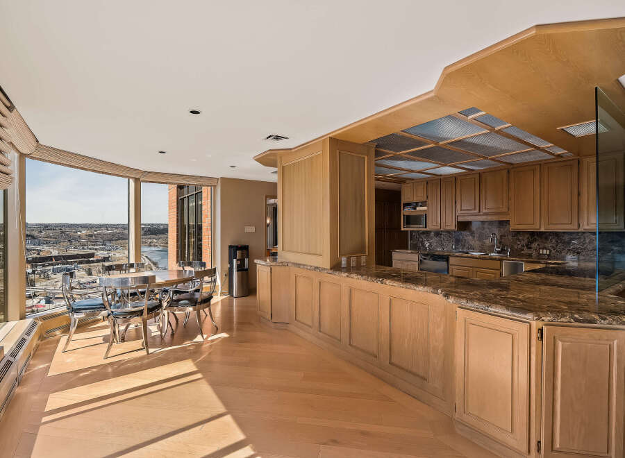 Experience breathtaking panoramic views from this stunning condo, featuring a spacious dining area with a table and chairs overlooking a cityscape and river.