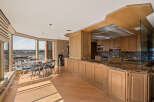Experience breathtaking panoramic views from this stunning condo, featuring a spacious dining area with a table and chairs overlooking a cityscape and river.