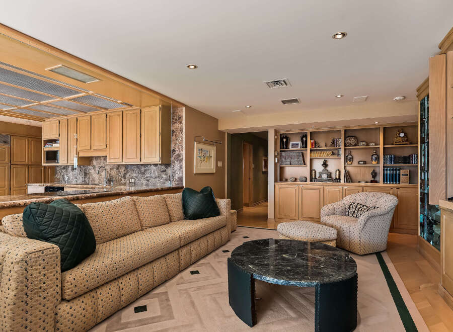 This spacious living area features a comfortable, patterned sofa complemented by a dark green accent pillow and a matching ottoman.