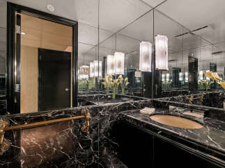 Experience opulent luxury in this stunning bathroom, featuring a sleek black marble vanity and a large mirrored wall that amplifies the space.