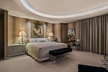 Experience luxury in this master suite featuring a king-sized bed with plush bedding and elegant striped wallpaper.