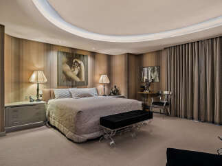 Experience luxury in this master suite featuring a king-sized bed with plush bedding and elegant striped wallpaper.