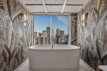 Experience luxury in this stunning bathroom featuring a freestanding soaking tub with breathtaking city views.