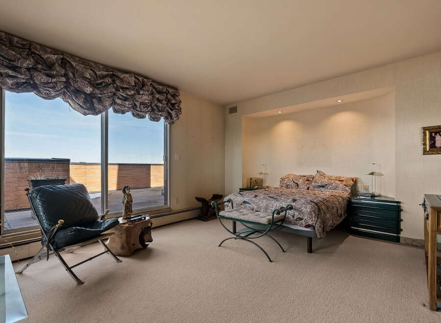 Experience luxurious living in this stunning bedroom featuring a king-sized bed with a vibrant, patterned comforter.