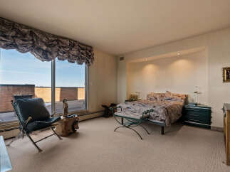 Experience luxurious living in this stunning bedroom featuring a king-sized bed with a vibrant, patterned comforter.