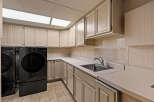 This spacious laundry room features a convenient sink and ample counter space, perfect for folding clothes.