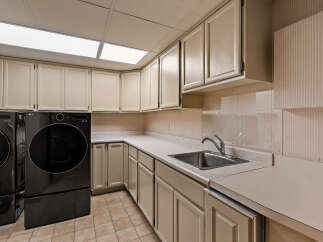 This spacious laundry room features a convenient sink and ample counter space, perfect for folding clothes.
