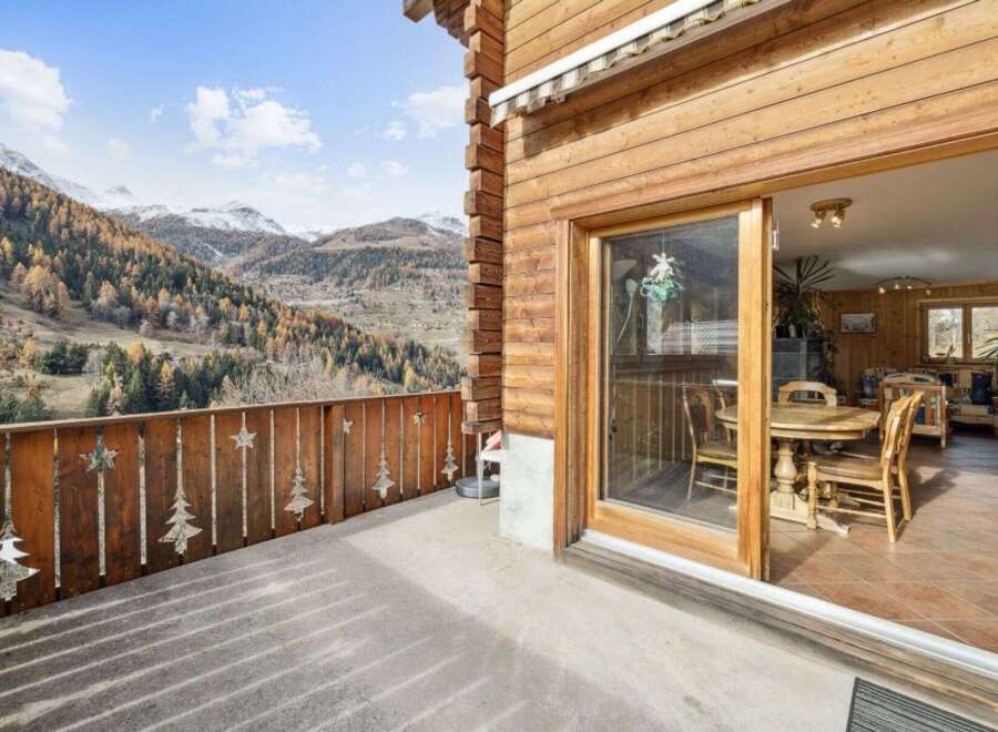Experience breathtaking mountain views from this charming wooden chalet's balcony, perfect for enjoying crisp alpine air.
