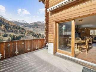 Experience breathtaking mountain views from this charming wooden chalet's balcony, perfect for enjoying crisp alpine air.