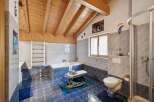 This charming bathroom features a vaulted wooden ceiling and elegant blue and grey tiled walls.