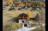 Nestled amidst the vibrant autumn foliage of the Swiss Alps, this charming wooden chalet offers a picturesque retreat.