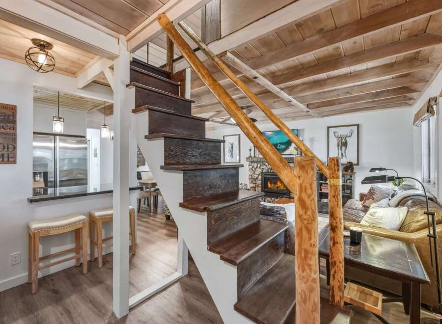Experience rustic charm in this inviting living space, featuring a cozy fireplace and a unique wooden staircase.