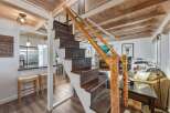 Experience rustic charm in this inviting living space, featuring a cozy fireplace and a unique wooden staircase.