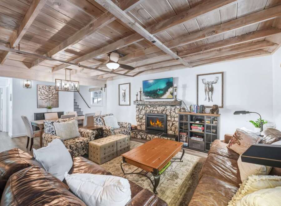 Experience rustic charm in this inviting living room, featuring a stone fireplace and a beamed wood ceiling.