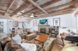 Experience rustic charm in this inviting living room, featuring a stone fireplace and a beamed wood ceiling.